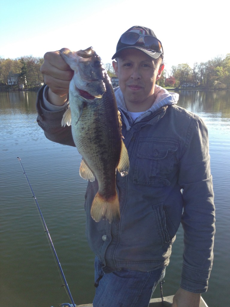 Fisherman holds largemouth bass from ball pond