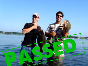 two guys wading in salt marsh with flounder